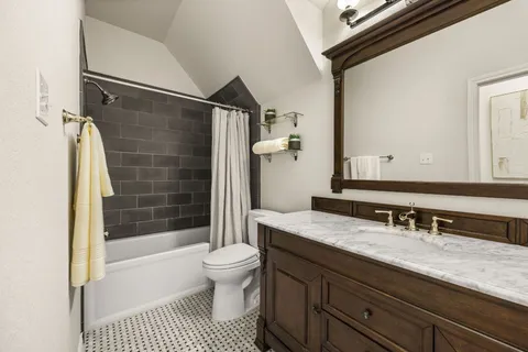 a bathroom with a granite countertop sink a toilet a mirror and shower