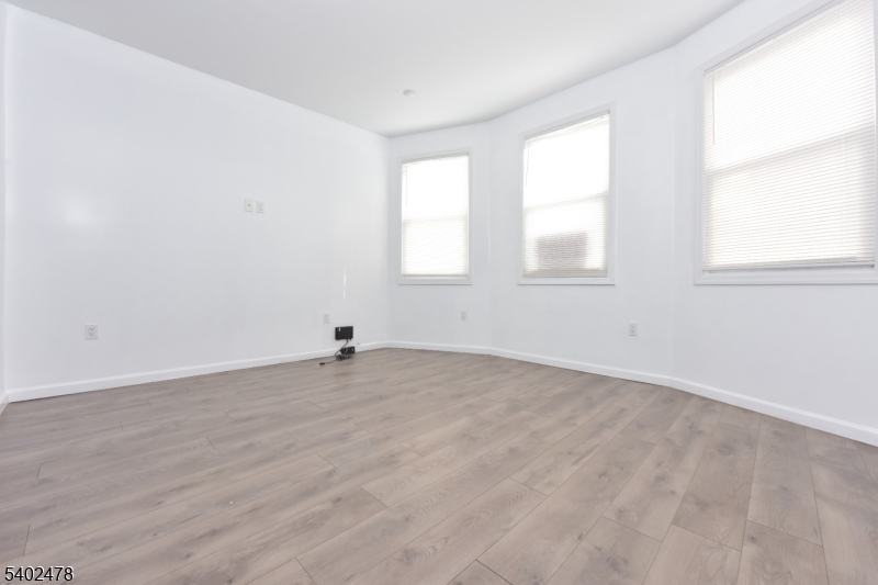 473 Grove Street, Unit 1 Irvington, NJ 07111 - Photo 15 of 17 an empty room with wooden floor and windows