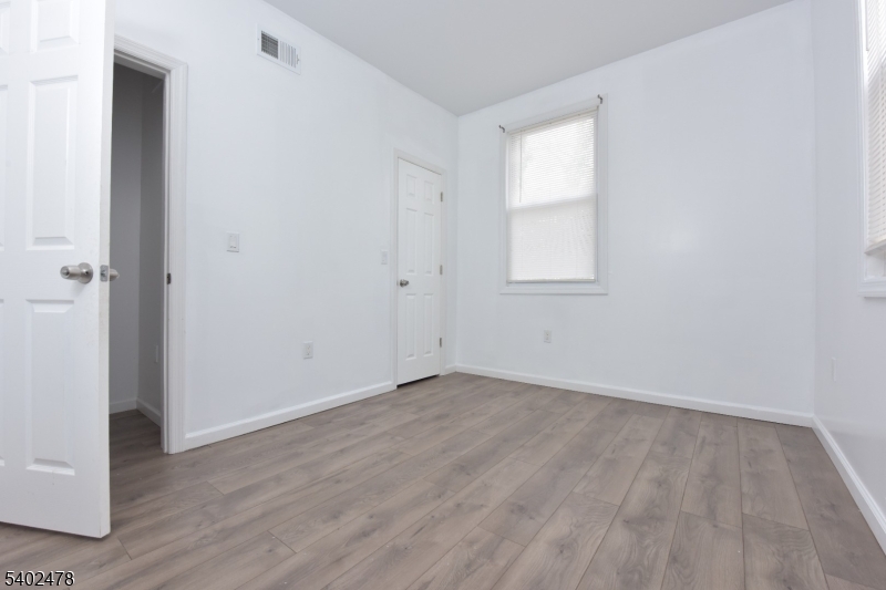 473 Grove Street, Unit 1 Irvington, NJ 07111 - Photo 17 of 17 an empty room with wooden floor and windows