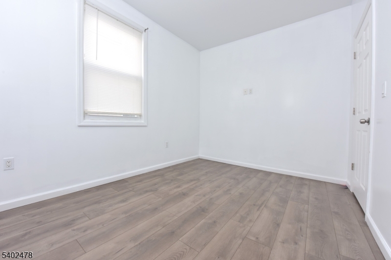 473 Grove Street, Unit 1 Irvington, NJ 07111 - Photo 3 of 17 an empty room with wooden floor and windows