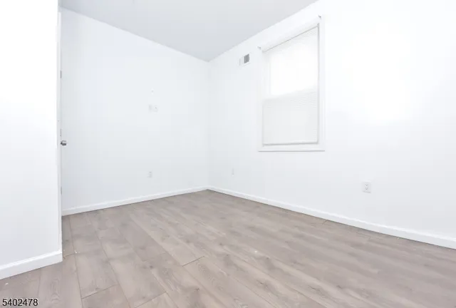 a view of a small space with wooden floor and a window