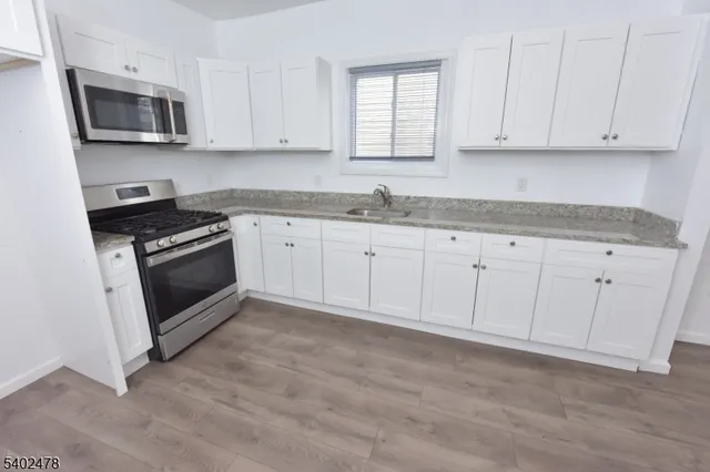 a kitchen with granite countertop white cabinets a sink and dishwasher