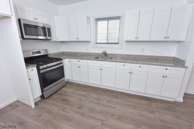 473 Grove Street, Unit 1 Irvington, NJ 07111 - Photo 10 of 17 a kitchen with granite countertop white cabinets a sink and dishwasher