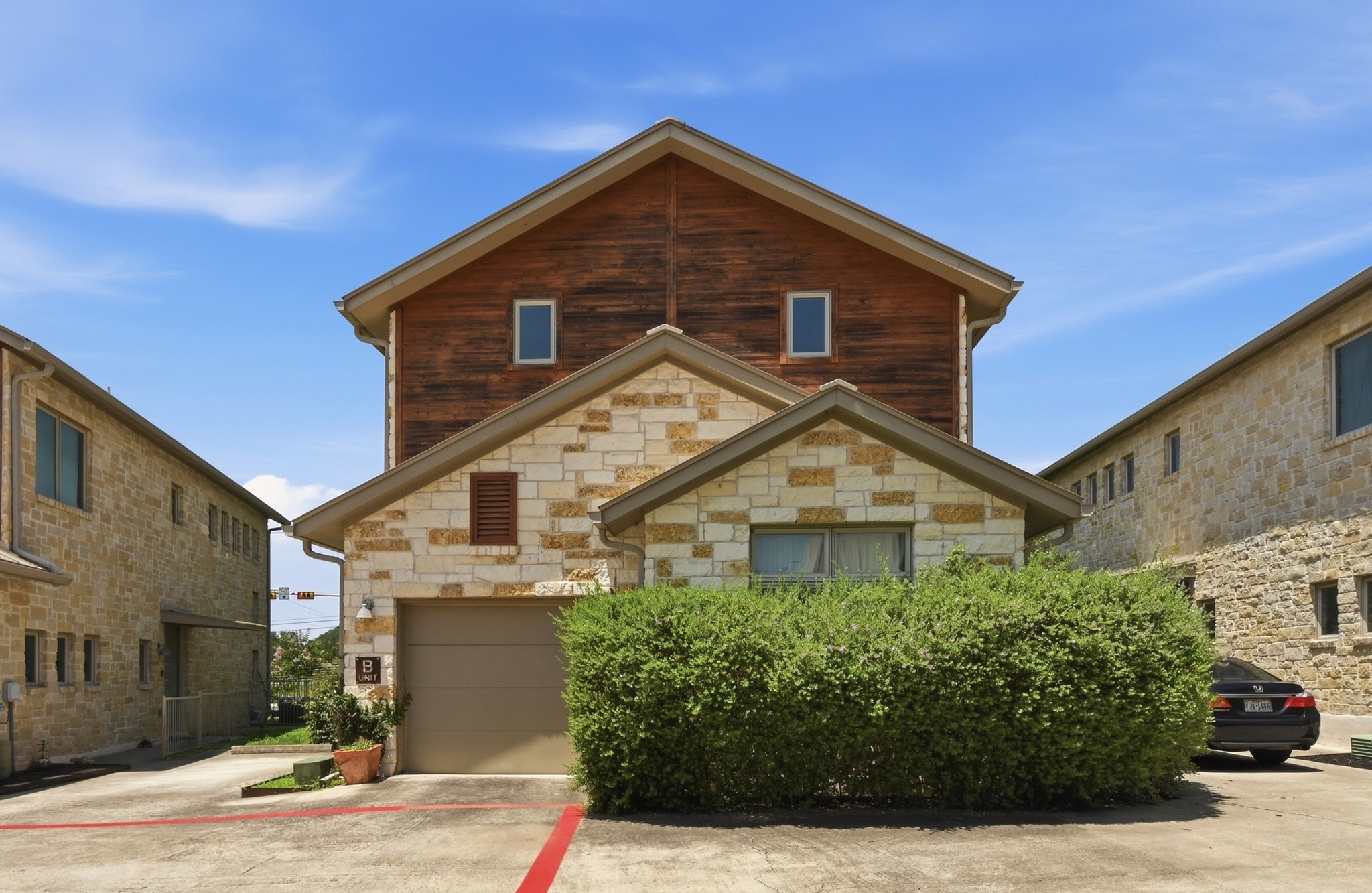 592 Farm To Market 967, Unit B Buda, TX 78610 - Photo 2 of 26 Beautifully designed with a timeless blend of stone and natural wood accents, this stylish townhome offers standout curb appeal, manicured landscaping, and the convenience of an attached garage.