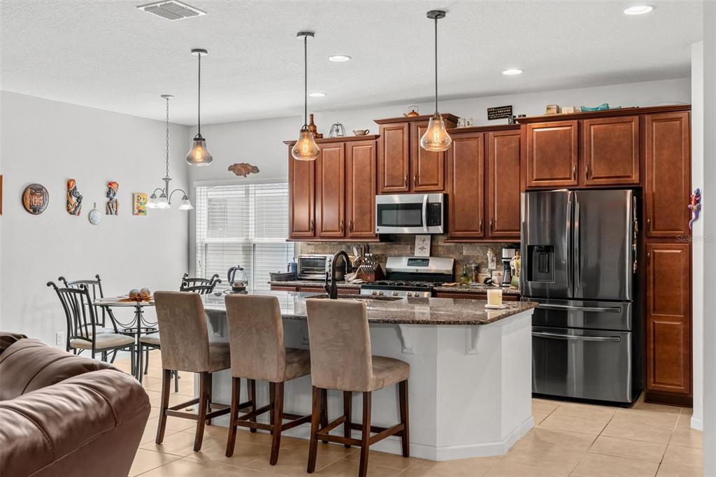 2085 Lula Road Minneola, FL 34715 - Photo 22 of 39 a kitchen with stainless steel appliances granite countertop a refrigerator a stove a sink a dining table and chairs