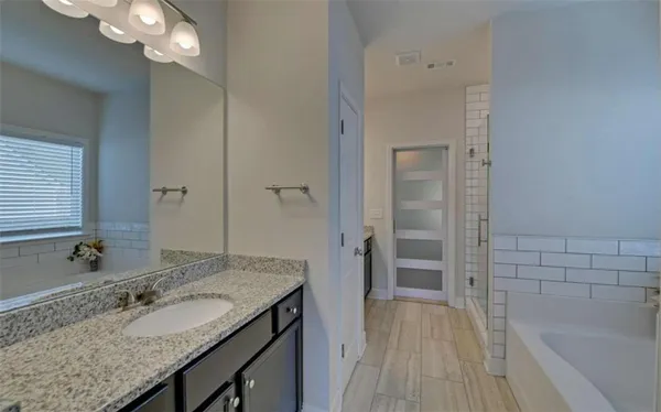a bathroom with a granite countertop sink a mirror and a bathtub