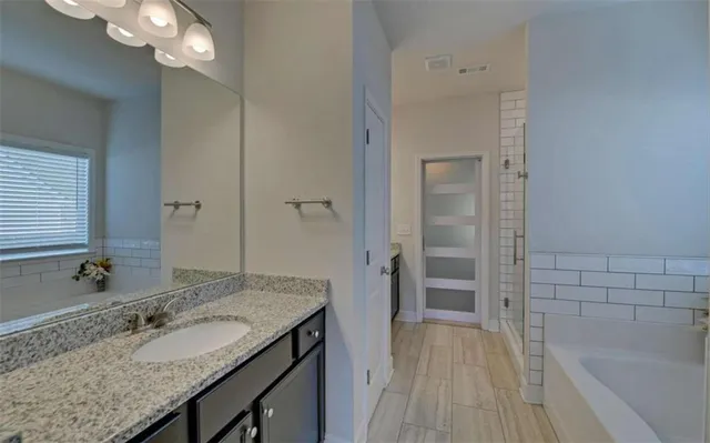 a bathroom with a granite countertop sink a mirror and a bathtub