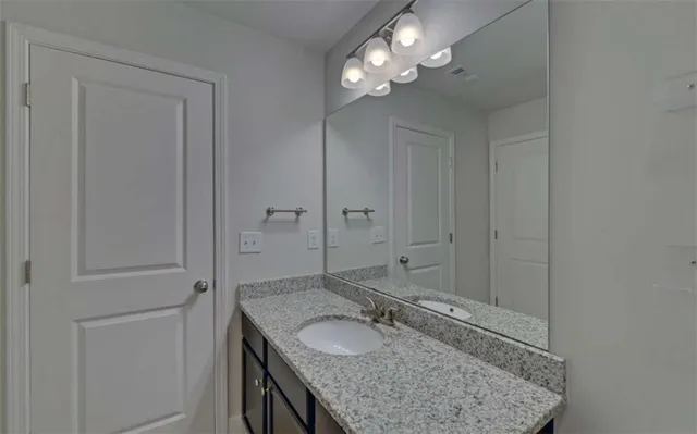 a bathroom with a granite countertop sink a toilet and shower
