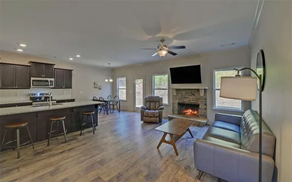 a living room with furniture a fireplace a flat screen tv and kitchen view