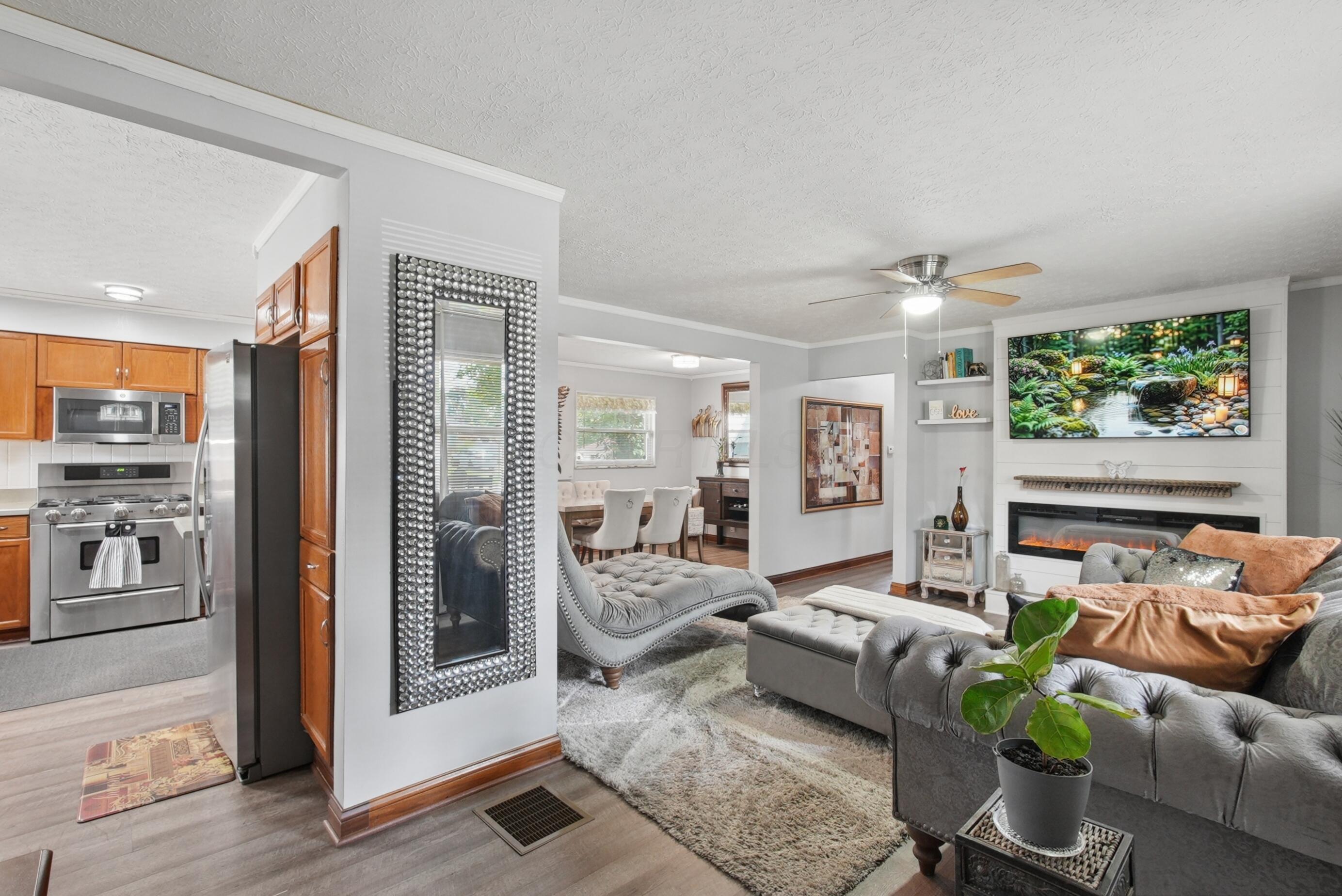 1636 Courtright Road Columbus, OH 43227 - Photo 17 of 35 Living space featuring an open concept, luxury vinyl plank flooring, a ceiling fan, and a floor to ceiling custom built-in electric fireplace with a mantel