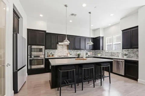 a kitchen with kitchen island granite countertop a sink and stainless steel appliances