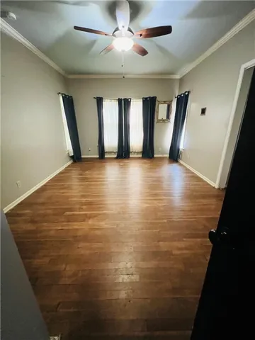 a view of an empty room with window and wooden floor