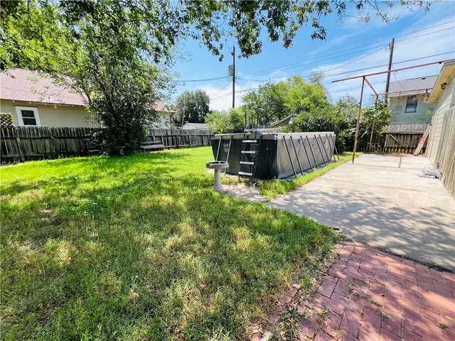 a view of a backyard with wooden fence and a large tree