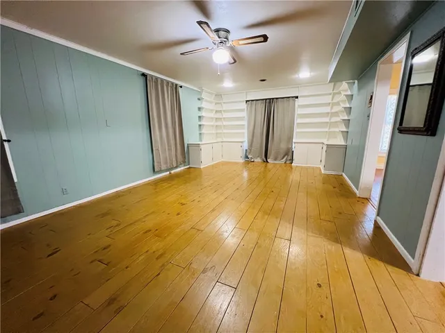 a large room with wooden floor and ceiling fan
