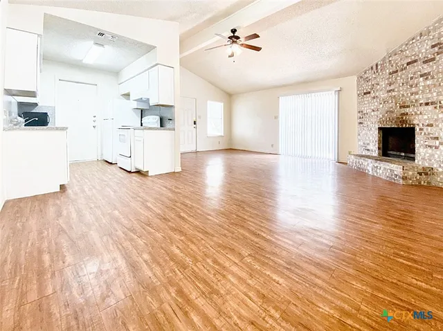 a view of a kitchen with wooden floor and a fireplace