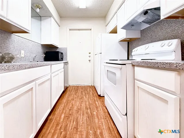 a kitchen with white cabinets and sink