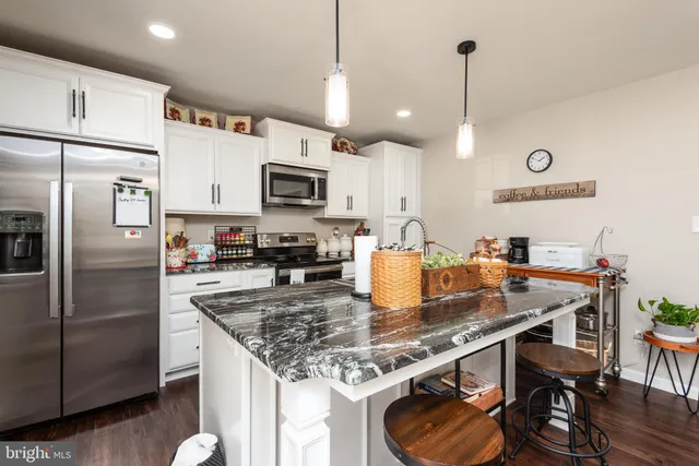 a kitchen with kitchen island granite countertop a sink a center island stainless steel appliances and cabinets