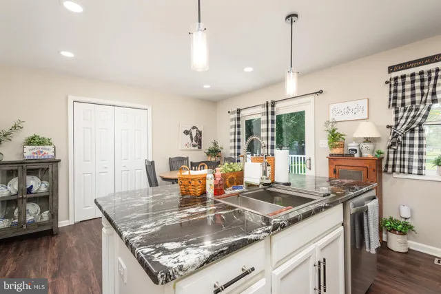a kitchen with stainless steel appliances granite countertop a stove a sink and a dining table with white cabinets
