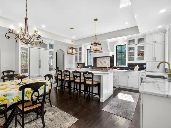 a open kitchen with stainless steel appliances granite countertop a stove a sink a dining table and chairs with wooden floor