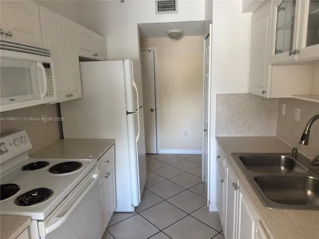 a kitchen with refrigerator and white cabinets