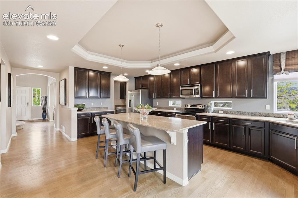 2264 Reed Grass Way Colorado Springs, CO 80915 - Photo 13 of 50 a kitchen with stainless steel appliances granite countertop a stove top oven a sink dishwasher a dining table and chairs with wooden floor