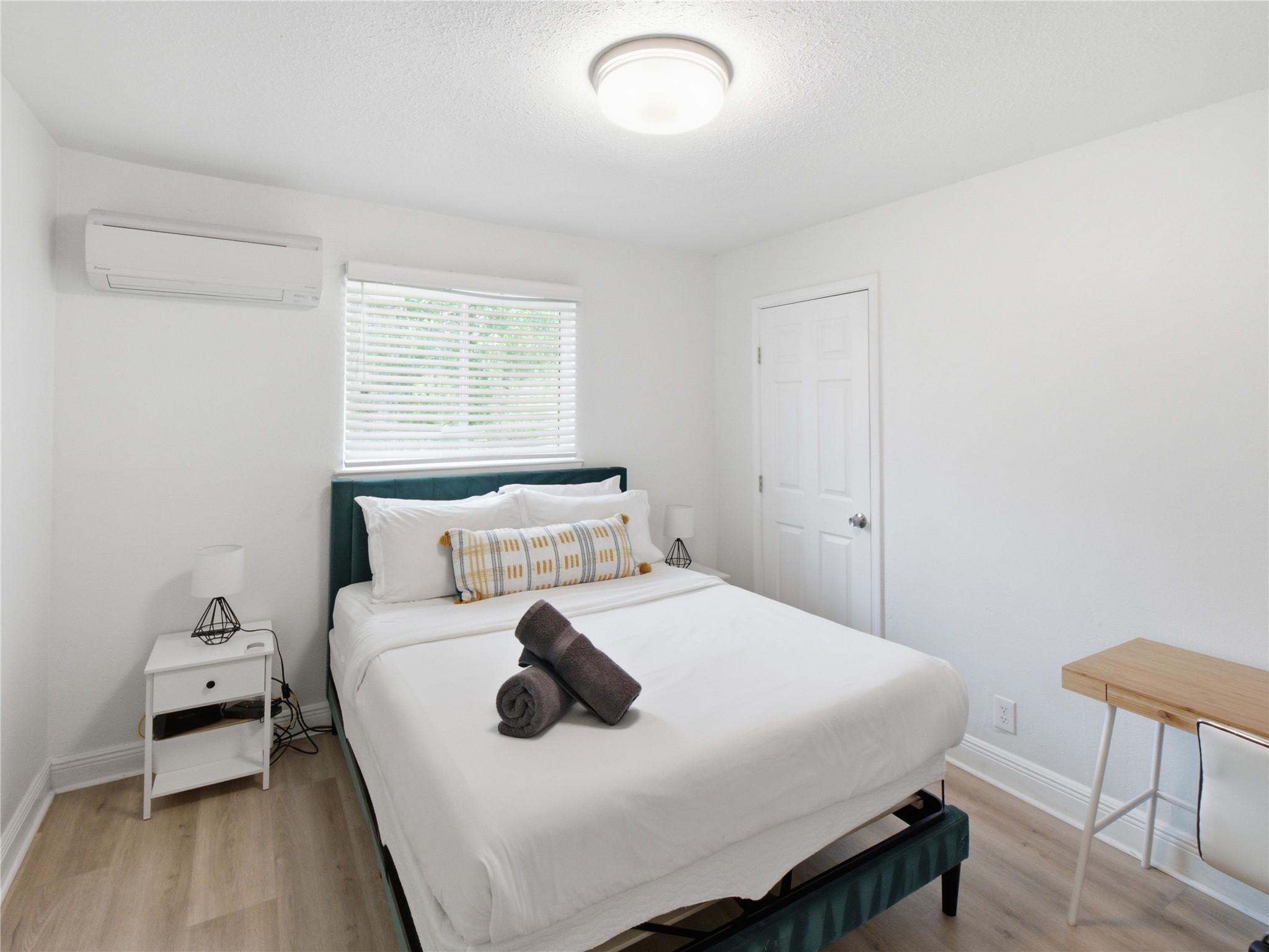 1108 Jolena Circle Austin, TX 78721 - Photo 8 of 21 Natural light filters into this bedroom, featuring sleek wood-look flooring and a modern bed frame.