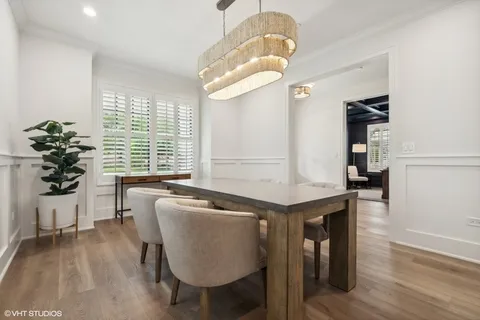 a dining room with wooden floor a chandelier a wooden table and chairs