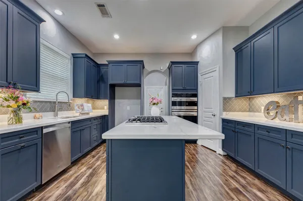 a kitchen with kitchen island granite countertop a sink stove and cabinets
