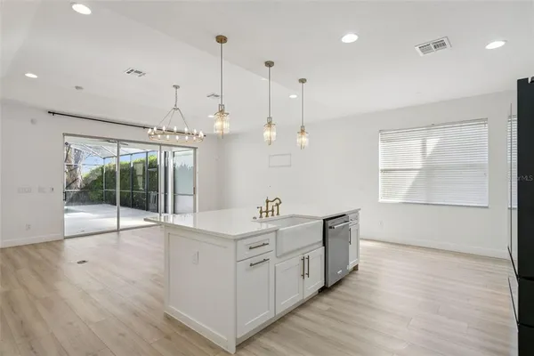 an empty room with a chandelier fan and windows