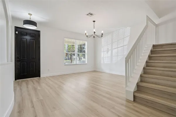 a large kitchen with kitchen island granite countertop a stove a sink a refrigerator and white cabinets with wooden floor