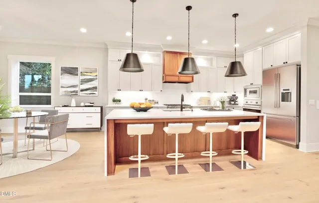 a kitchen with stainless steel appliances kitchen island granite countertop a table chairs and a sink