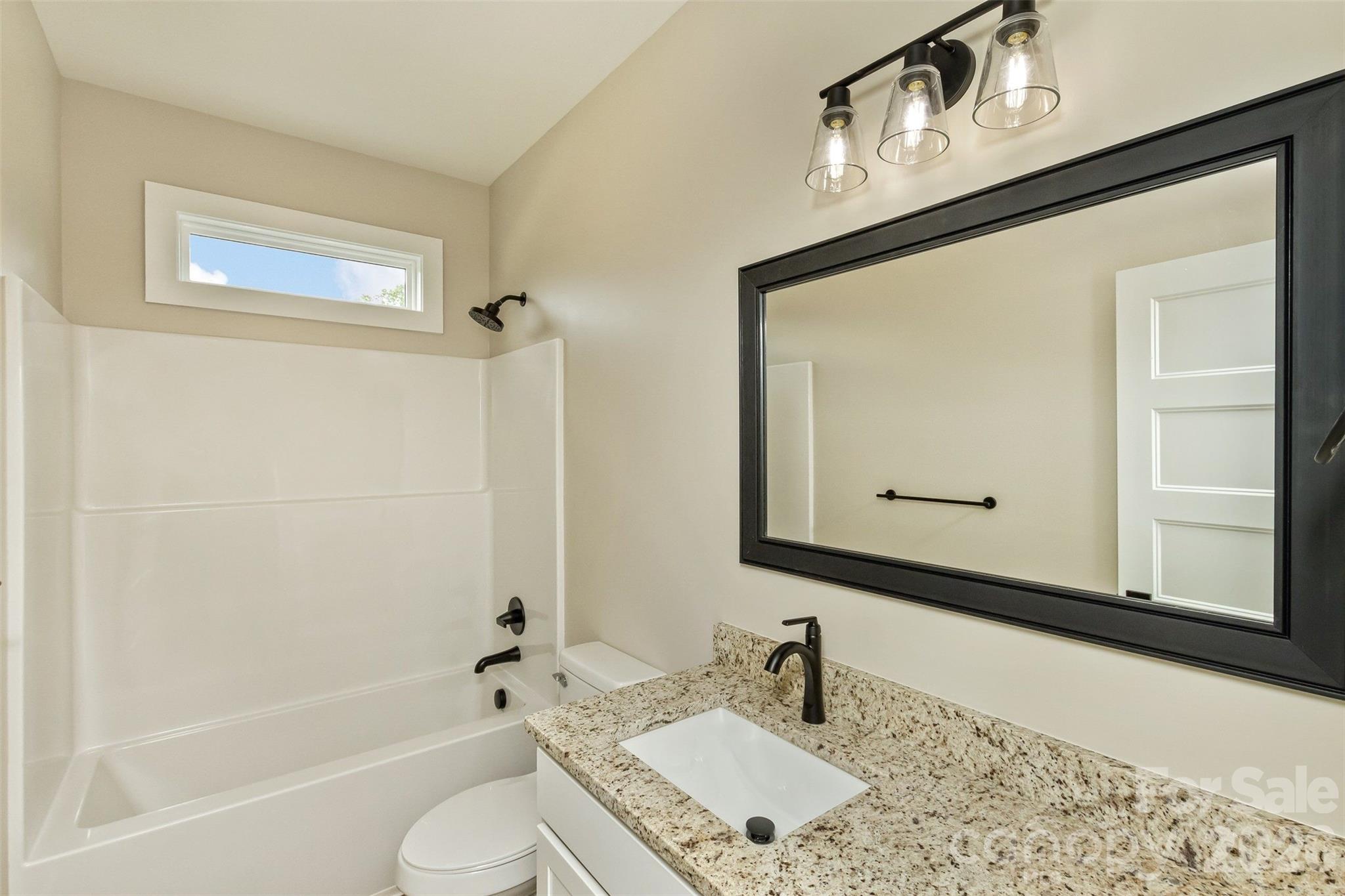112 Peyton Elaine Road Clyde, NC 28721 - Photo 19 of 35 a bathroom with a granite countertop sink mirror vanity and toilet