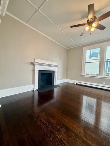 an empty room with wooden floor fireplace and windows