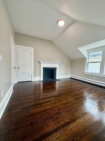 a view of empty room with wooden floor and fireplace