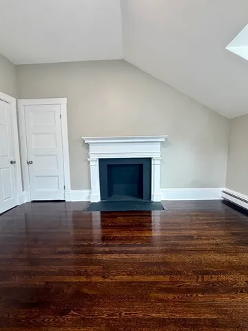 a view of empty room with wooden floor and fireplace