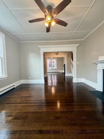 a view of empty room with wooden floor and fan