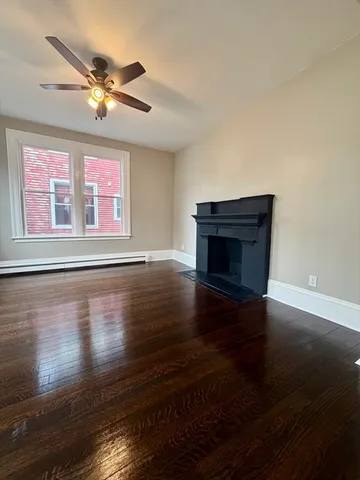 a view of a livingroom with wooden floor a ceiling fan and a window