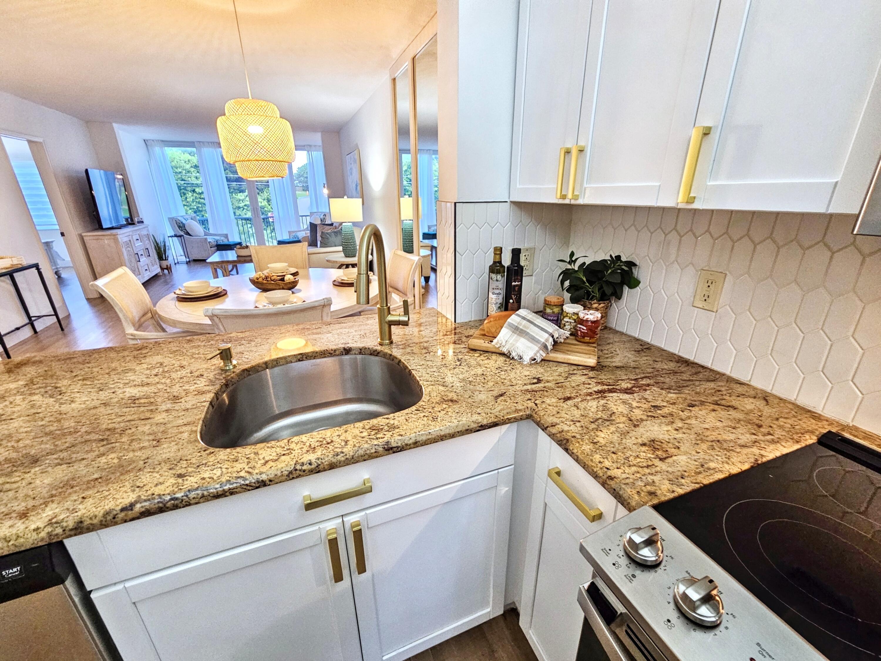 6530 North Ocean Boulevard, Unit 205 Ocean Ridge, FL 33435 - Photo 12 of 53 a kitchen with granite countertop a sink a stove and cabinets