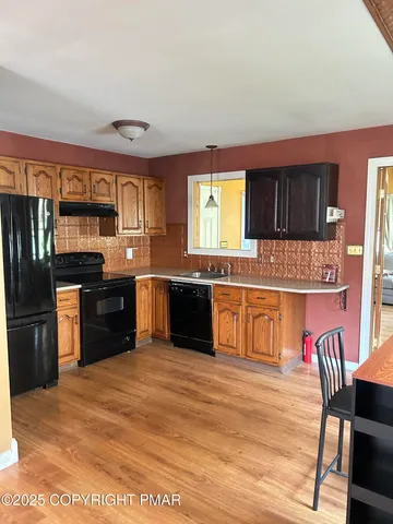 a kitchen with stainless steel appliances granite countertop a stove top oven a sink dishwasher a dining table and chairs with wooden floor