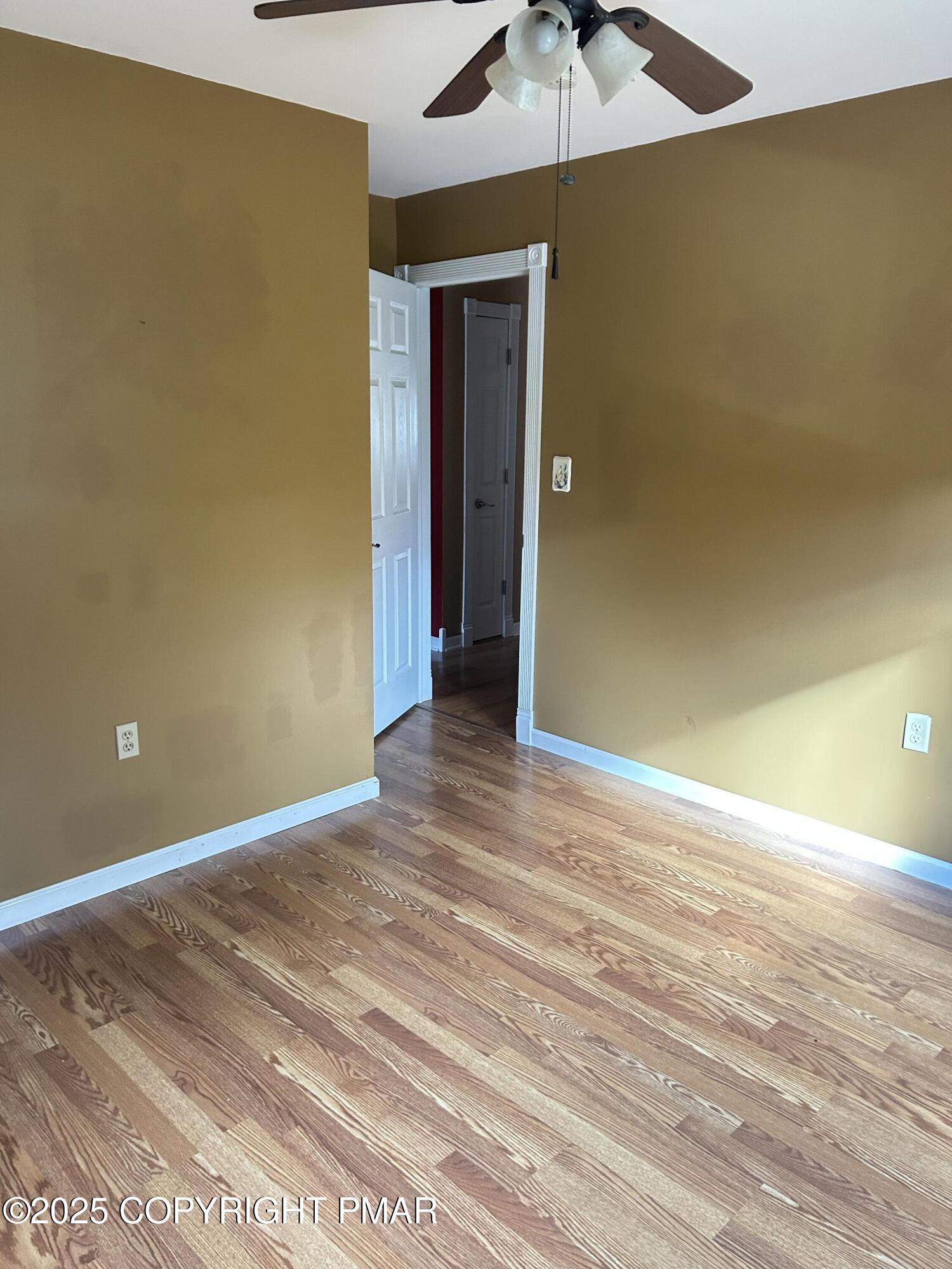 1152 Steele Circle Bushkill, PA 18324 - Photo 19 of 39 an empty room with a chandelier fan and wooden floor