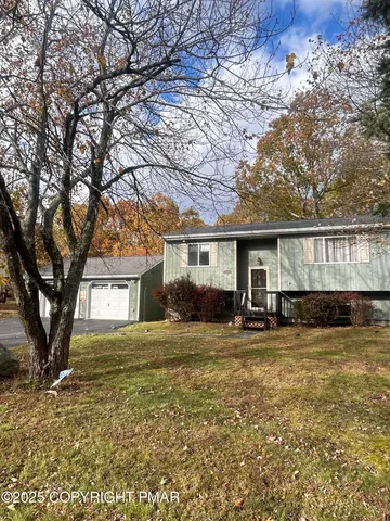 a view of a house with a large tree and a yard