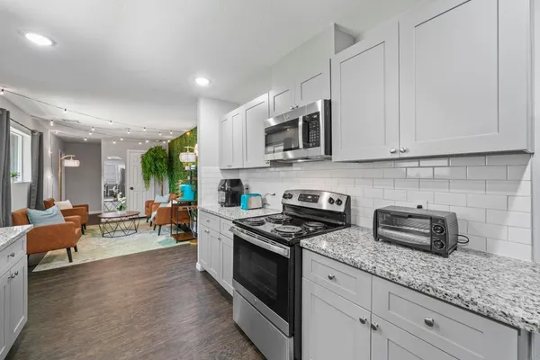 a kitchen with stainless steel appliances granite countertop a stove a sink dishwasher and a microwave oven with white cabinets