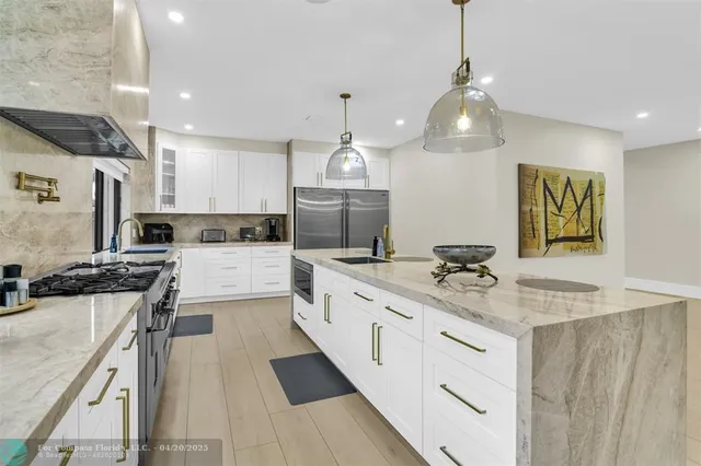 a kitchen with stainless steel appliances kitchen island granite countertop a dining table and chairs in it