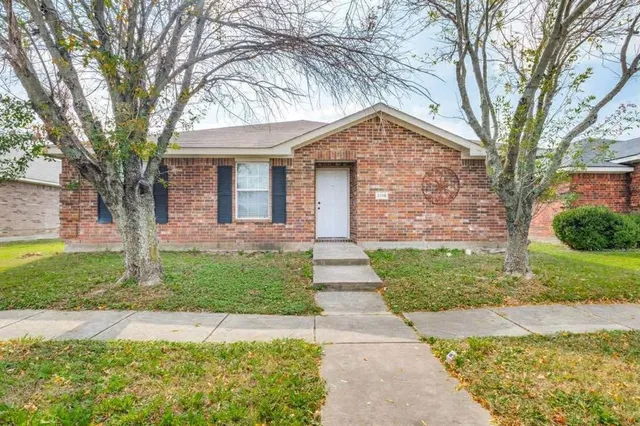 a front view of a house with a garden and trees