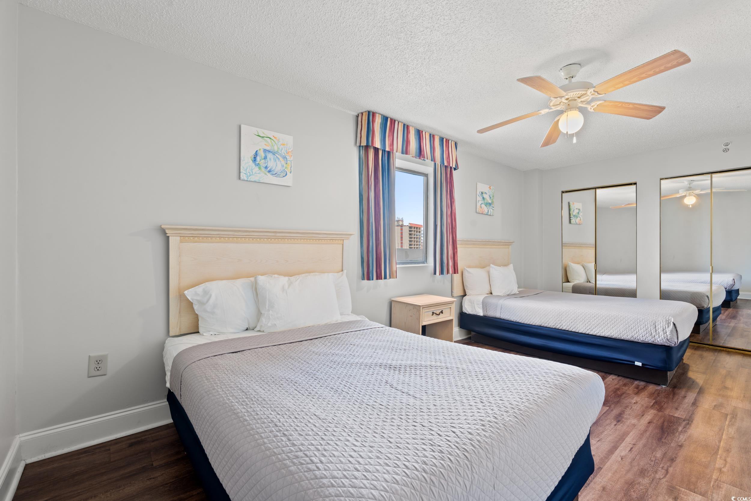 201N 74th Avenue North, Unit 601 Myrtle Beach, SC 29572 - Photo 13 of 35 Bedroom with multiple closets, a textured ceiling, dark wood-type flooring, and a ceiling fan