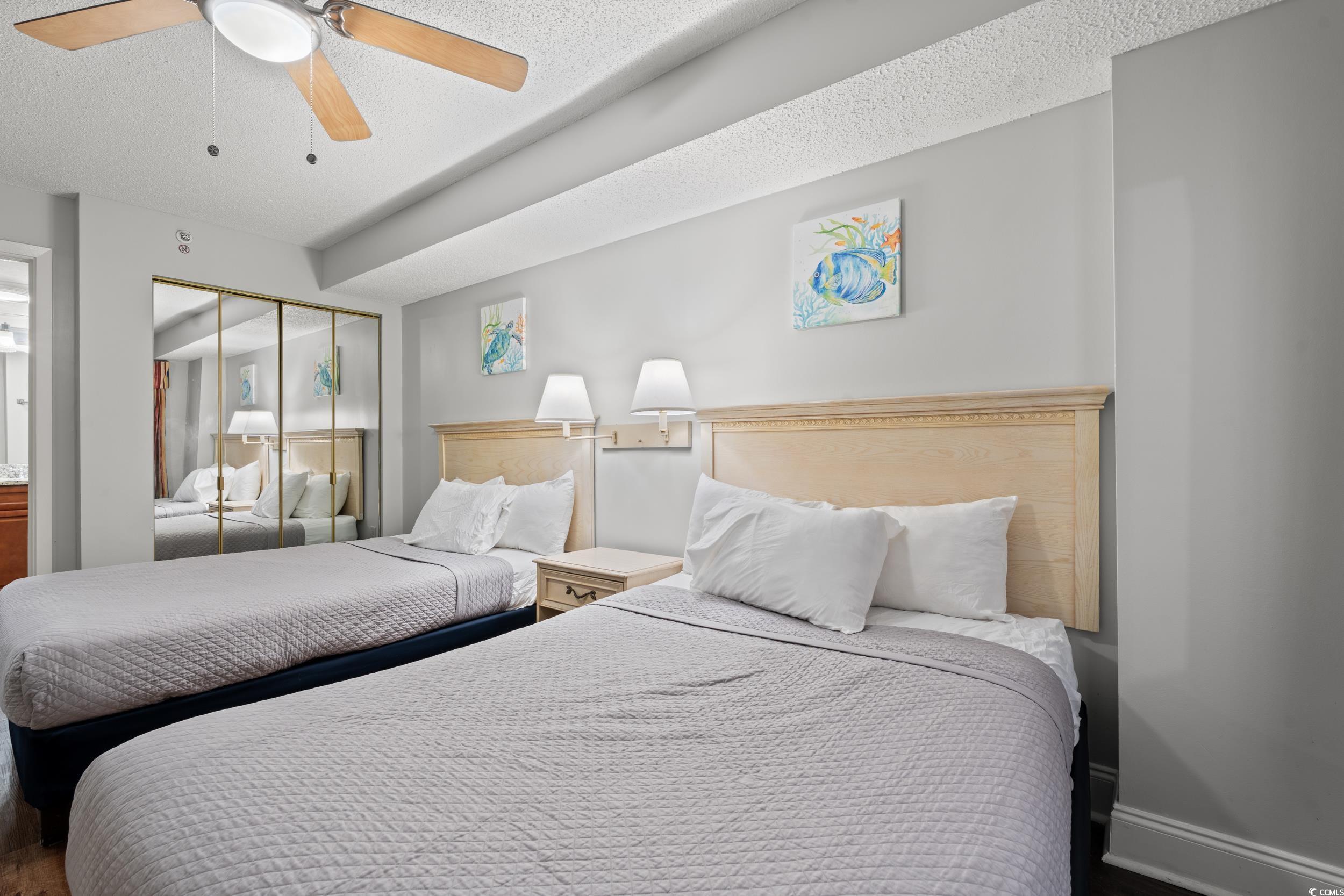 201N 74th Avenue North, Unit 601 Myrtle Beach, SC 29572 - Photo 15 of 35 Bedroom featuring a closet, ensuite bath, a textured ceiling, ceiling fan, and wood finished floors