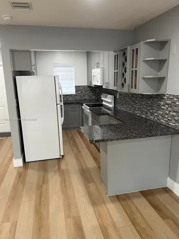 a kitchen with stainless steel appliances granite countertop a sink a stove a refrigerator and cabinets