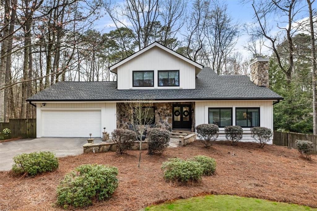 2415 Roxburgh Drive Roswell, GA 30076 - Photo 2 of 62 a front view of a house with patio outdoor seating and covered with trees