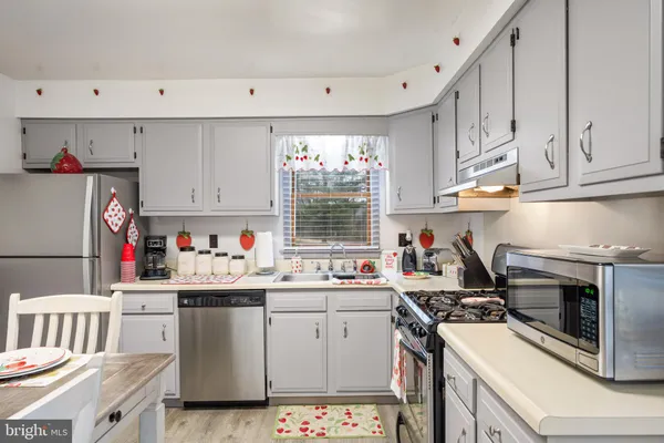 a kitchen with granite countertop a sink cabinets stainless steel appliances and a window