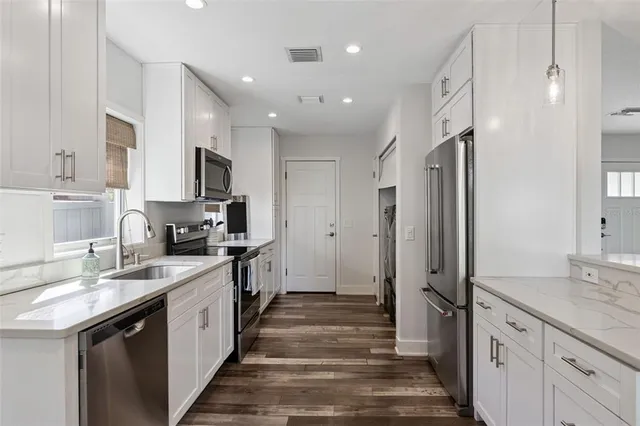 a large kitchen with a sink stainless steel appliances and cabinets